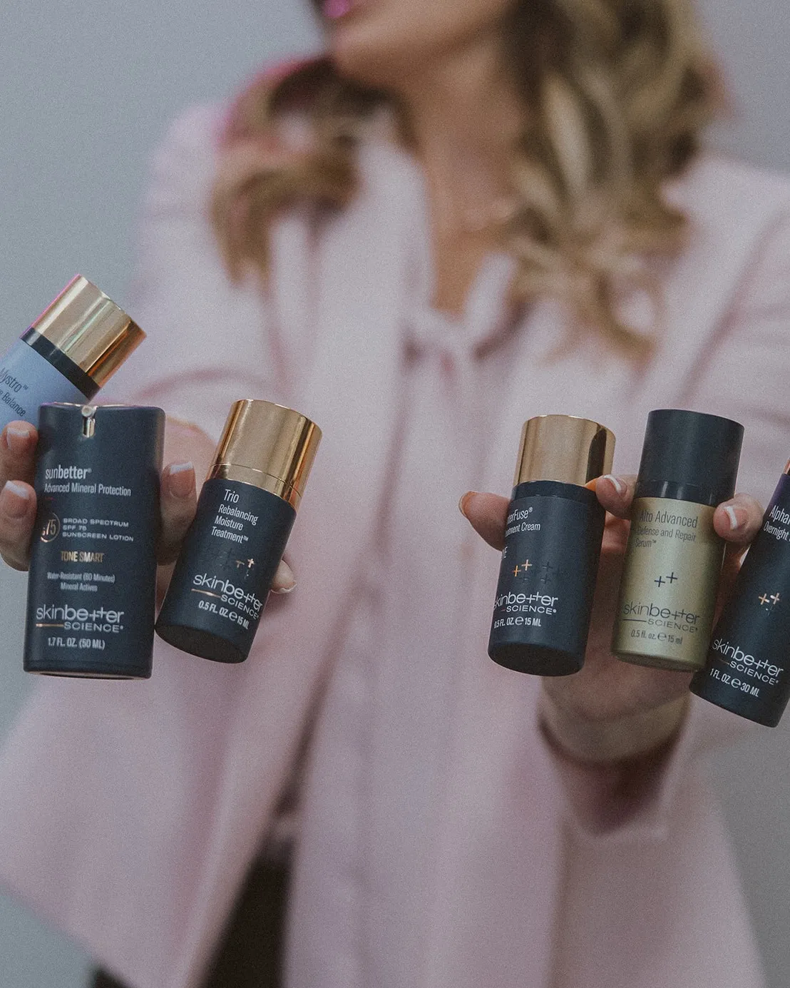 Amy holding six Skinbetter Science products out toward the camera.
