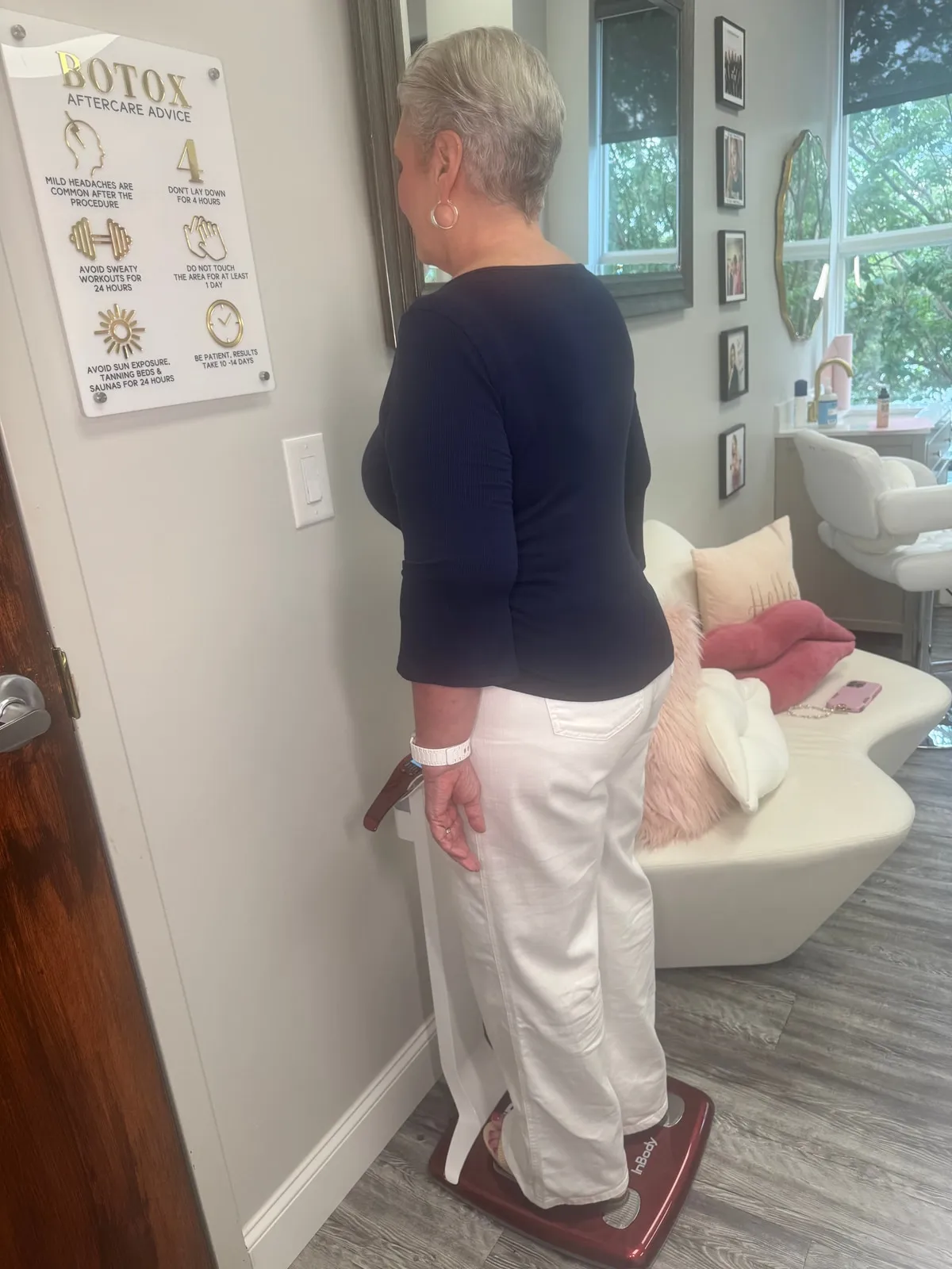 A client stands on the InBody body-composition scale at the medspa, seen from behind, with the treatment lounge beyond.