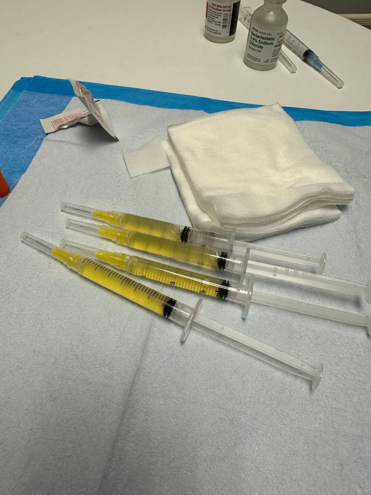 Four prepared PRP syringes, filled with golden plasma, laid out on a towel beside gauze and supplies at Amy's Harrisburg medspa.